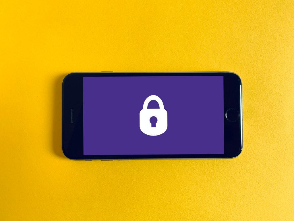 Celular con un candado sobre fondo violeta, sobre fondo amarillo Celular con un candado sobre fondo violeta, sobre fondo amarillo