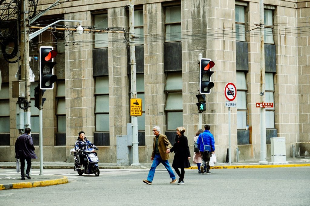 Gente en la calle con semáforos en rojo y un edificio de fondo