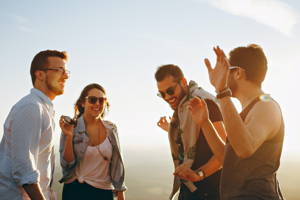 Tres hombres y una mujer bailando y sonriendo a la luz del Sol Tres hombres y una mujer bailando y sonriendo a la luz del Sol
