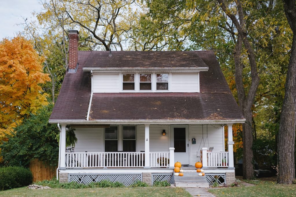 Casa pintada de blanco con tejas sobre una entrada arbolada y con pasto