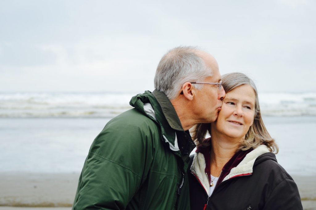 Hombre besando a mujer en la mejilla en la playa