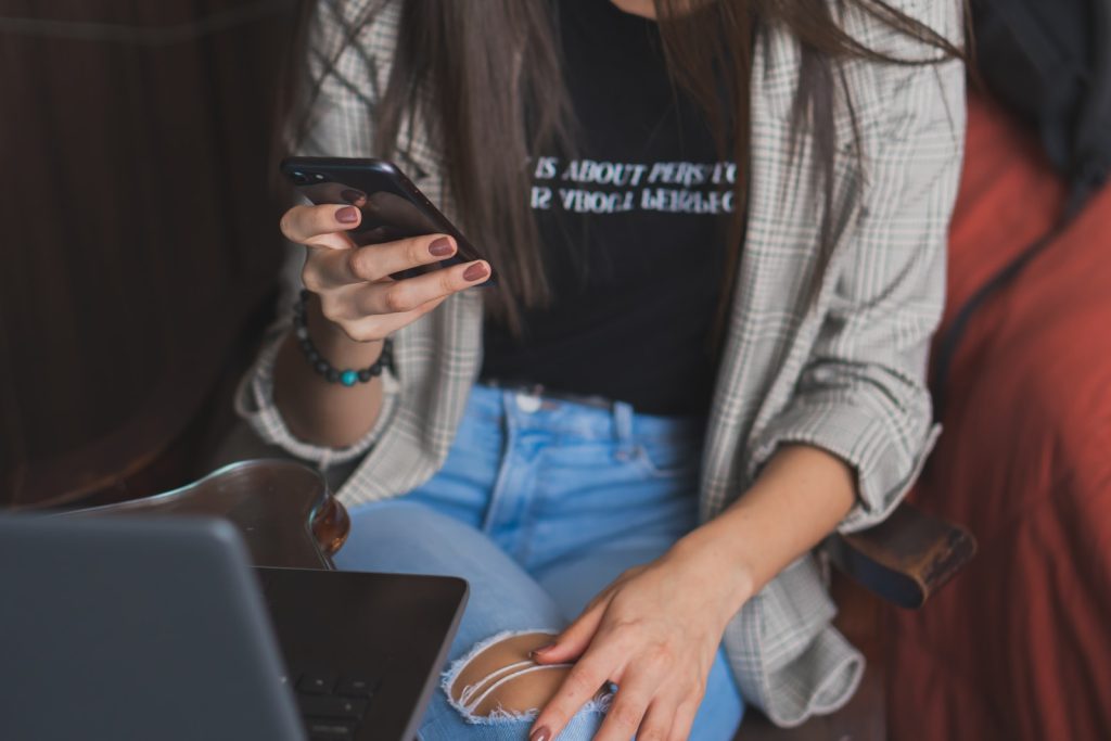 Mujer con jean y camisa sentada mirando el celular Mujer con jean y camisa sentada mirando el celular