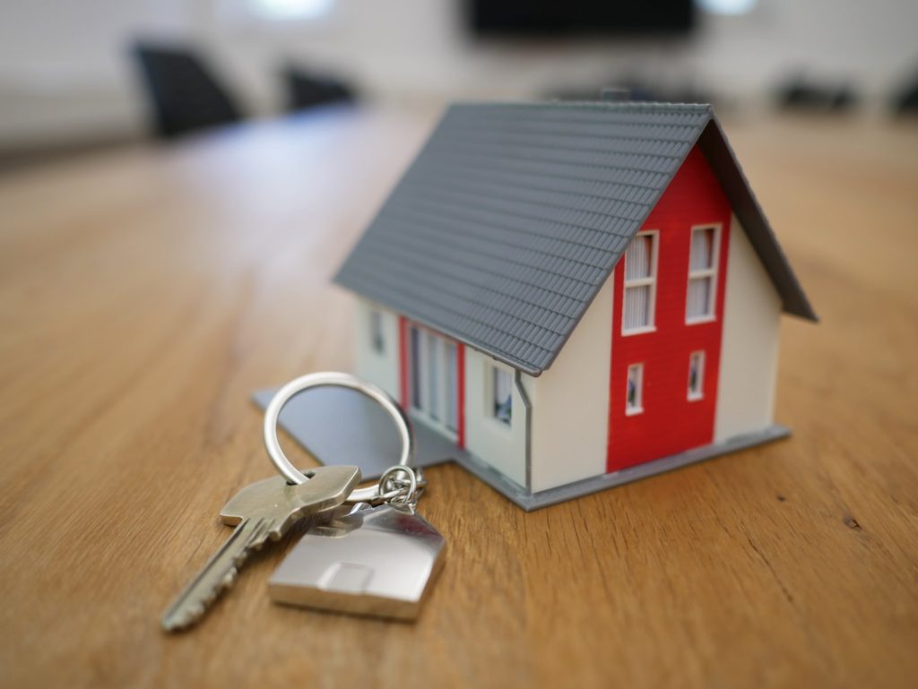 Casa de madera blanca y roja sobre mesa al lado de llaves