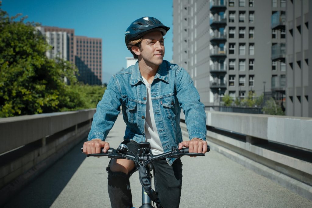 Hombre con campera de jean y casco andando en bicicleta