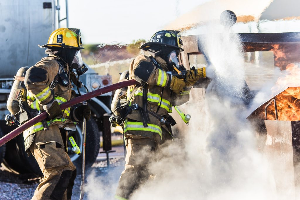 Tres bomberos apagando fuego en un incendio Tres bomberos apagando fuego en un incendio