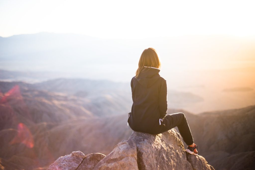 Mujer sentada en pico de montaña durante el día