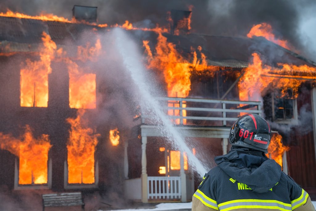 Bombero apagando fuego de una casa Bombero apagando fuego de una casa