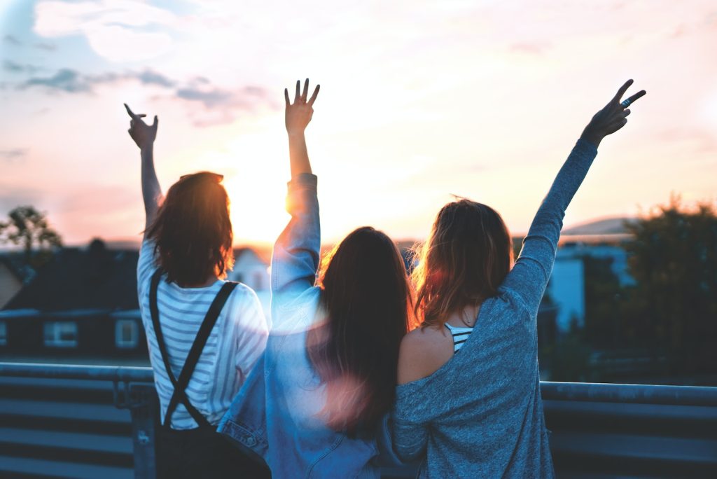 tres mujeres levantando los brazos mirando al horizonte